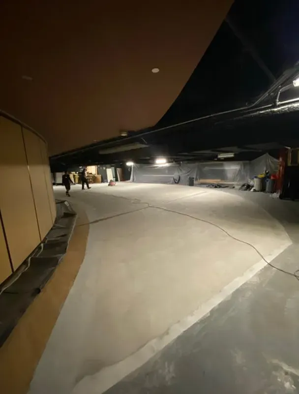 Concrete slab prepared and primed inside a darkened commercial auditorium