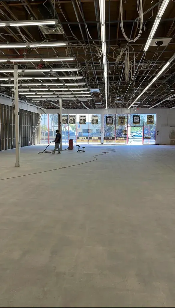 Large commercial floor being machine-polished, a worker visible in the distance