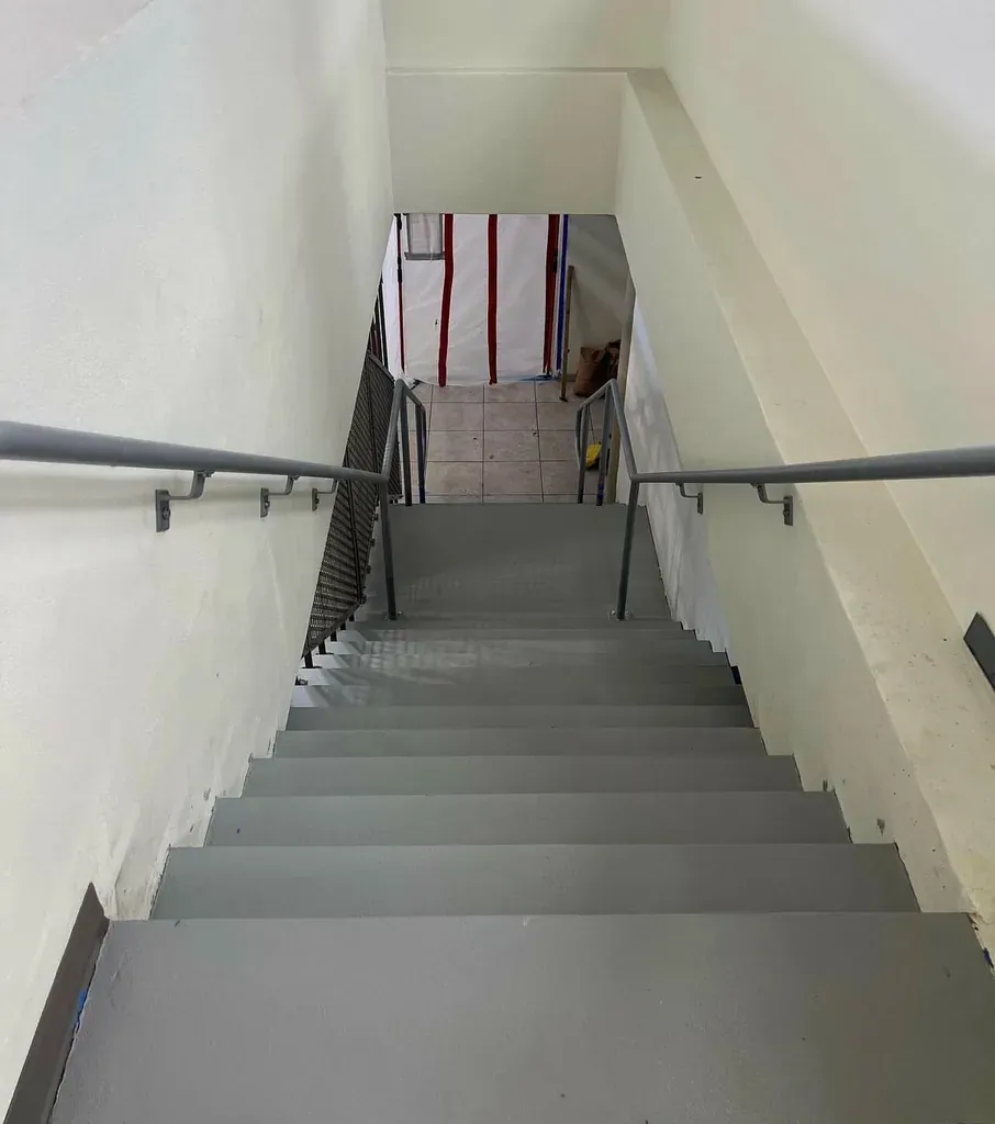 Interior stairwell with grey coated treads and risers and metal handrails