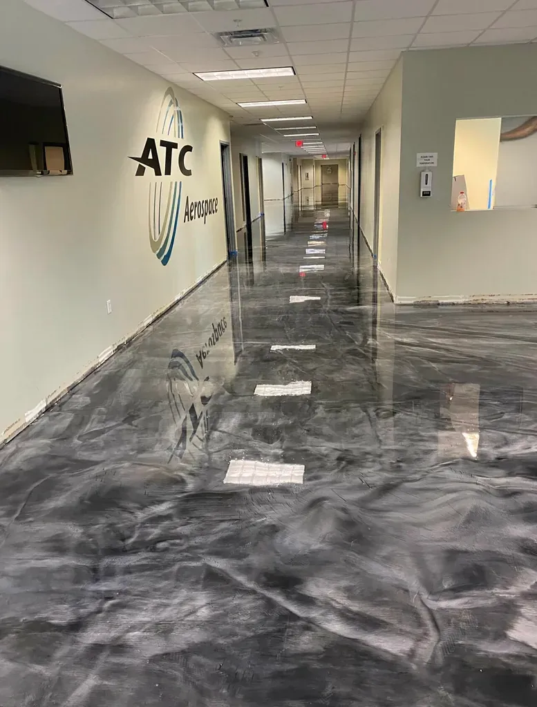 Corporate corridor with a dark grey metallic epoxy floor and company signage on the wall