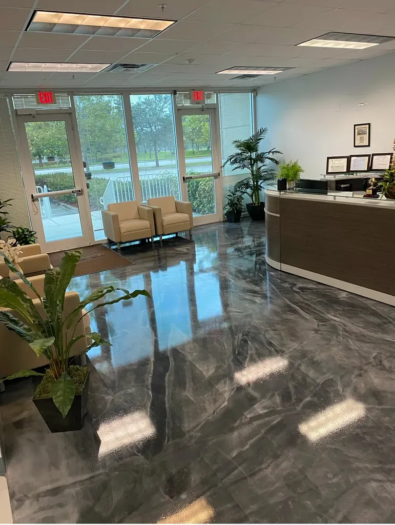 Office reception area with a grey metallic epoxy floor reflecting the seating and windows