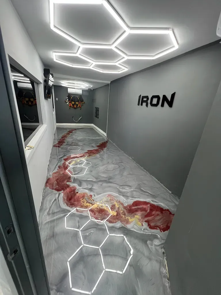 Gym interior with a grey metallic epoxy floor veined in red under hexagonal ceiling lights