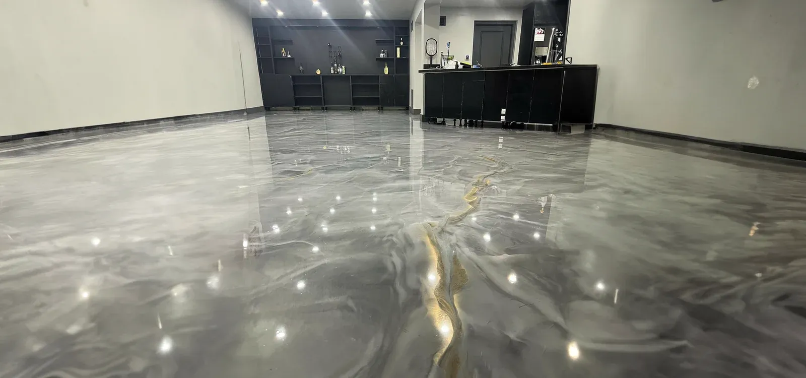 Mirror-finish metallic epoxy floor with grey marbling and gold veining, photographed at floor level