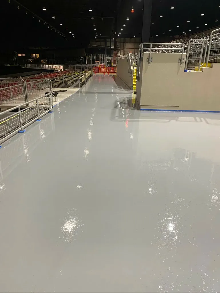 Large light grey coated rooftop deck photographed at night with perimeter railings