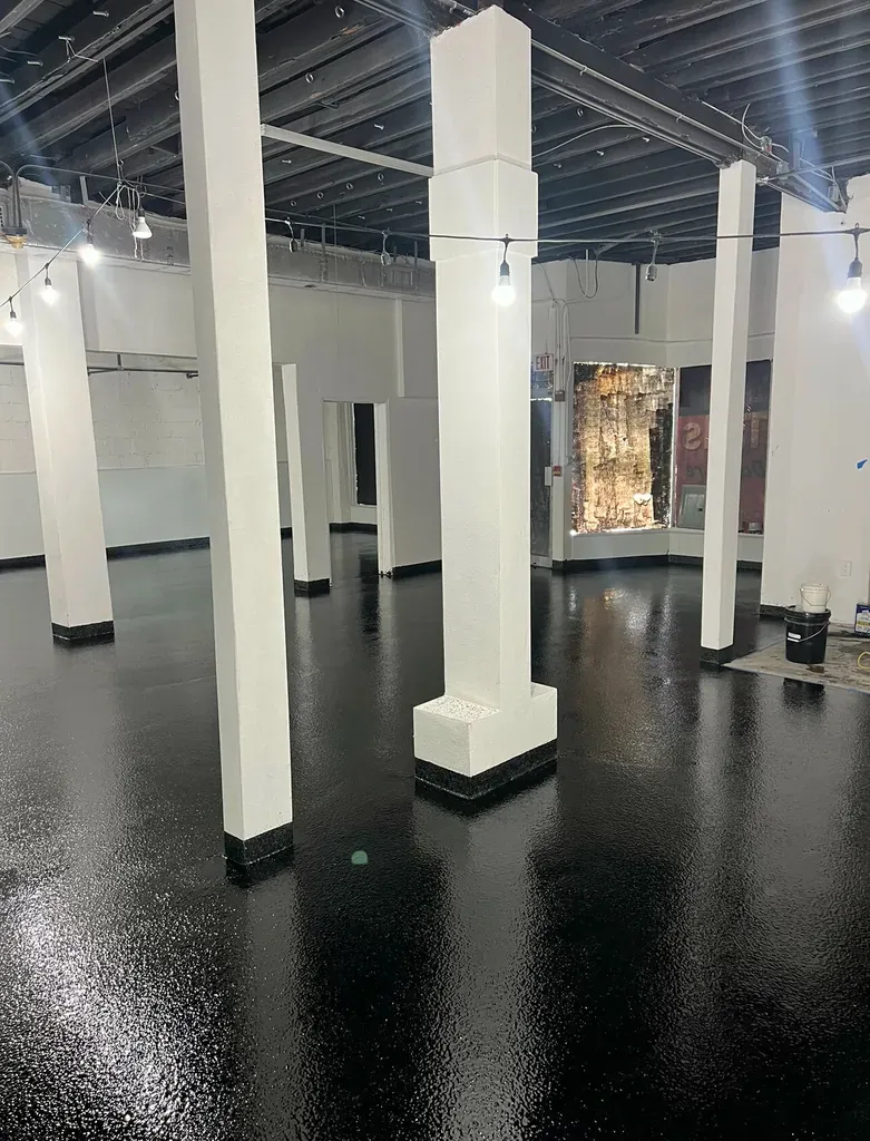 Open commercial hall with white columns over a mirror-black high-gloss epoxy floor